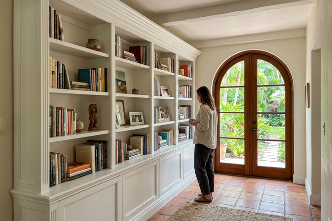 Finished custom white built-in bookcase with molding around a hallway in a Coral Gables home