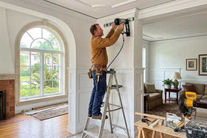 Carpenter installing baseboard trim in a South Miami family home